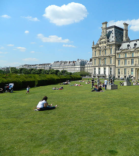 Paris park Paris, France - June 3, 2013: The Tuileries gardens in front and people lying on the grass in Paris. place des pyramides stock pictures, royalty-free photos & images