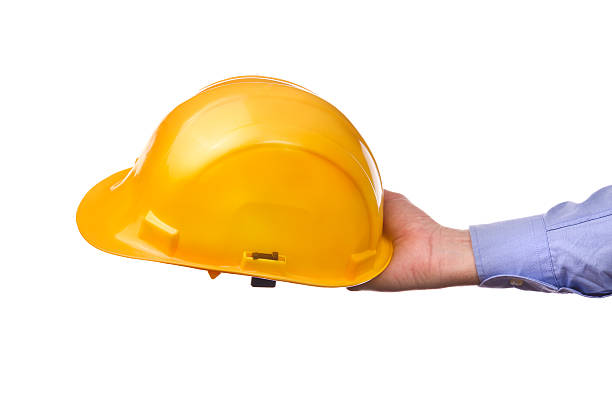 istock Male worker's hand holding yellow industrial protective helmet. 538904451