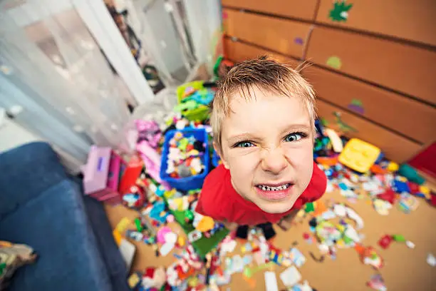 Portrait of a naughty and messy little boy. The boy looks angrily at the camera.