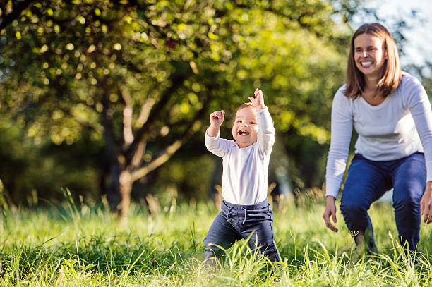 istock Mother holding her son making first steps, green nature 538907038