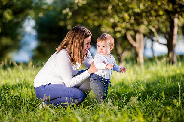 istock Mother holding her son making first steps, green nature 538908412