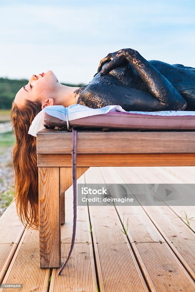 Woman sludge treatment during sunset Beautiful woman lying does sludge treatment. Beauty Spa Stock Photo
