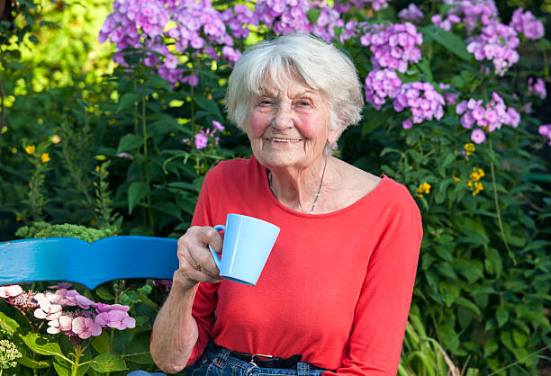 Feliz Grandma disfruta de un café en el jardín. - foto de stock