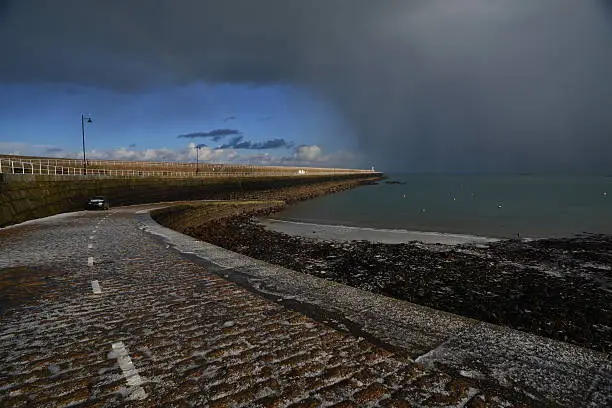Wide angle image of a pier just after a hailstorm moving over the sea.