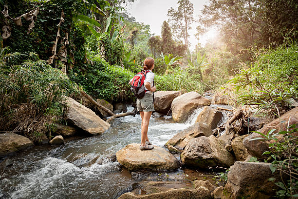 Woman with backpack hiking at rainforest river