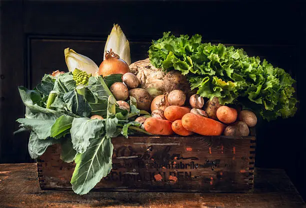 Photo of fresh vegetables in old  box over dark wooden wall