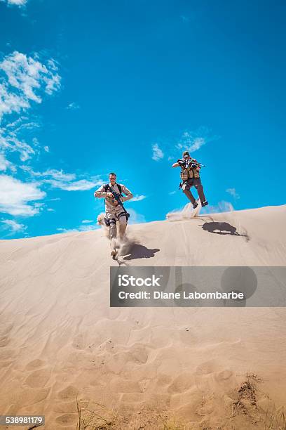 Two Special Operations Officers Jumping Off A Sand Hill Shooting Stock Photo - Download Image Now