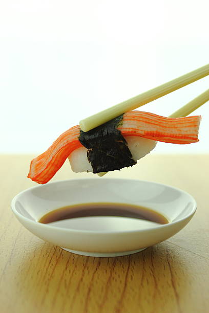 istock holding crab stick sushi roll with chopsticks and shoyu sauce 538984341