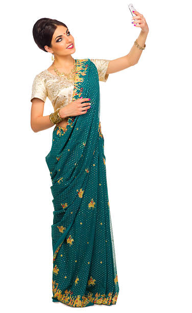 A green sari with gold trim on a dress form in front of a white background.