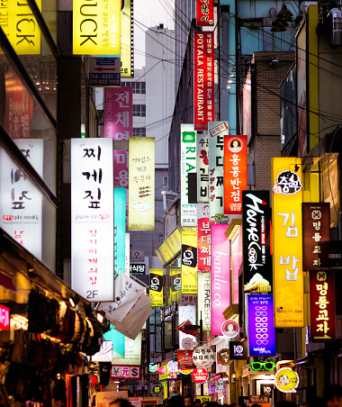 Multiple illuminated commercial signs in Seoul street at dusk. Photographed on Myeongdong street.