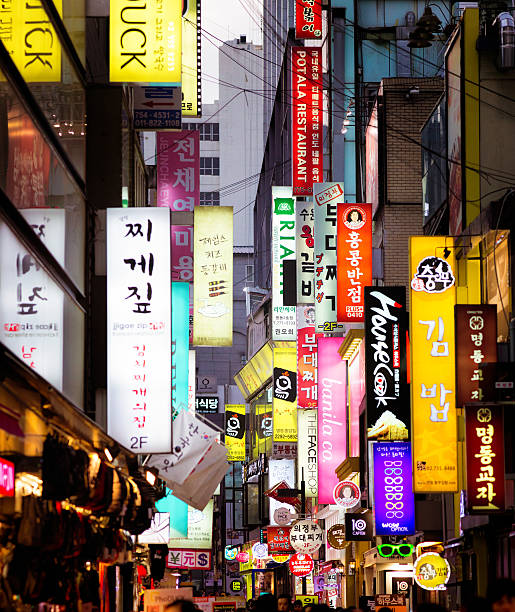 Multiple illuminated commercial signs in Seoul street at dusk Multiple illuminated commercial signs in Seoul street at dusk. Photographed on Myeongdong street. seoul stock pictures, royalty-free photos & images