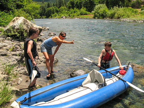 Woman advising young boys on kayaking in the river. Trinity River, California.