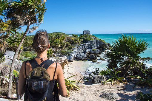 Woman taking in a view of El Castillo and the Caribbean coast. Mayan site of Tulum. Quintana Roo, Mexico.