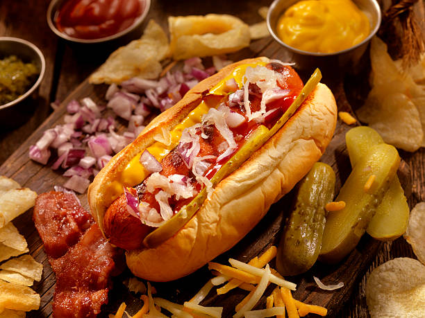hot-dog mit allen zutaten - cheese focus on foreground on top of portion stock-fotos und bilder