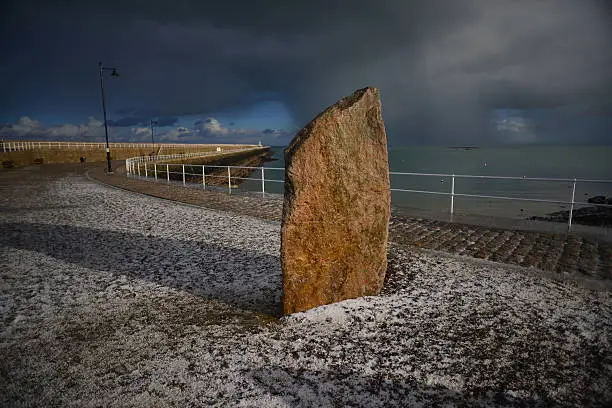Wide angle coastal image of a pier just after a hail storm moving on over the sea and horizon.