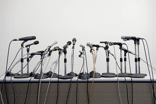 Press Conference Microphone Table A large group of microphones set up on a table for a press conference or public speaking event. press room stock pictures, royalty-free photos & images