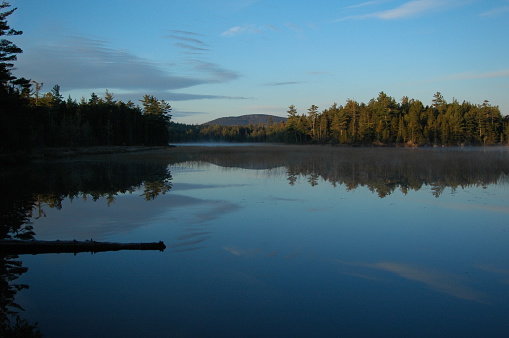 Still water, blue sky,  and reflections on a remote pond in New England