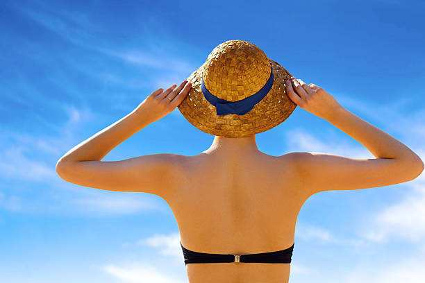istock Rear view young woman in sun hat standing and tanning 539014222