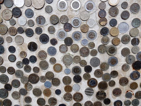 Positano, Salerno, Campania, Italy - March 13, 2016: various coins out over several countries around the world, cemented on a city wall