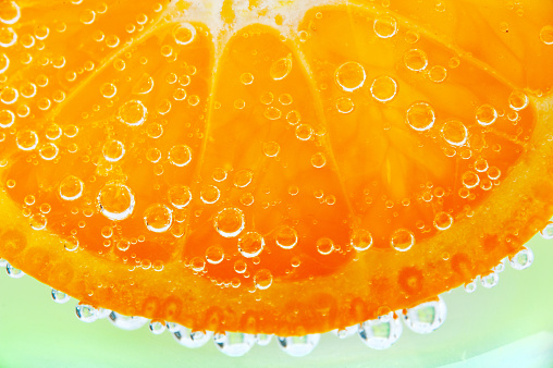 slice of orange in the water with bubbles