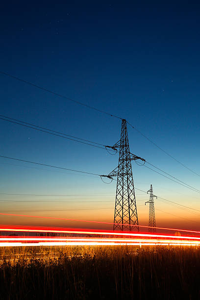 Pylons and traffic Pylons and electricity powerlines at night with traffic lights in front sunrise timelapse stock pictures, royalty-free photos & images