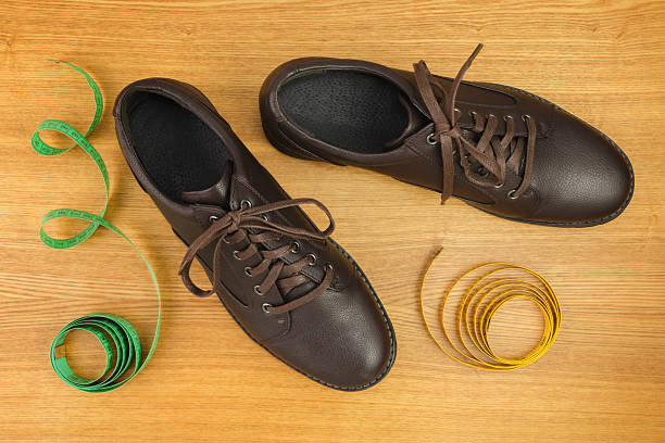 Object composition with a new men's shoes and measuring tapes on wooden polished background. 