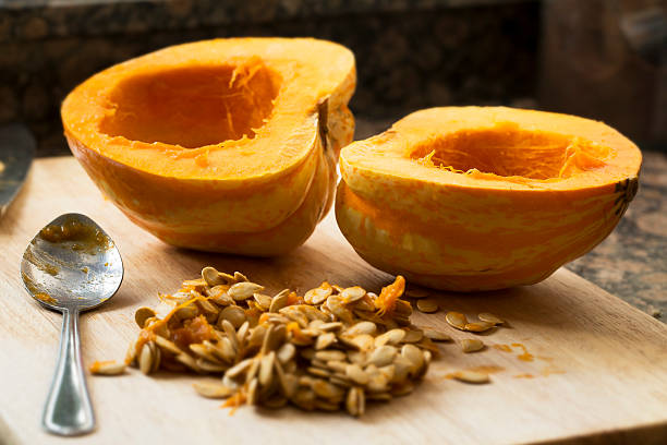 Cleaning Winter Squash Winter squash cut in half with spoon and seeds scooped out. acorn squash stock pictures, royalty-free photos & images