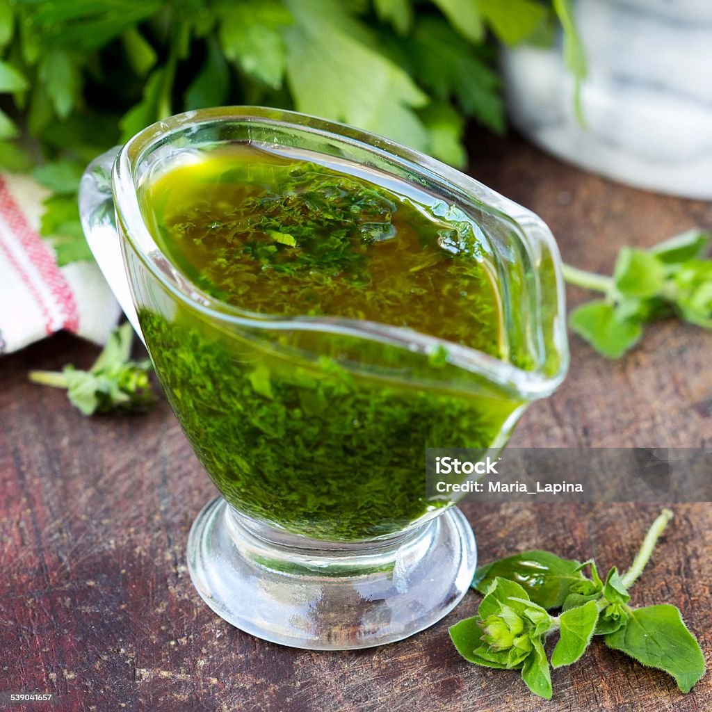 Green sauce marinade from herbs oregano, parsley, oil, tradition Green sauce marinade from herbs oregano, parsley, oil, traditional chimichuri in glass sauce-boat Backgrounds Stock Photo