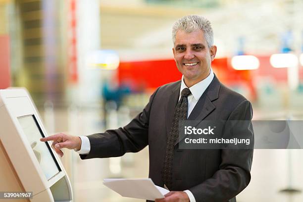 Mature Businessman Using Self Help Check In Machine Stock Photo - Download Image Now