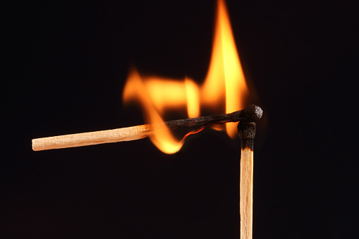 Small flame burning in two matches on a black background