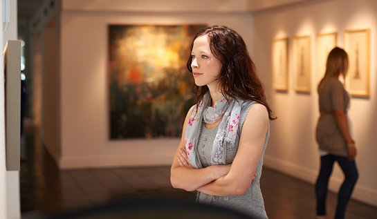 In an art center, visitors looks at the artist's modern art collection. Modern colorful paintings on exhibition.