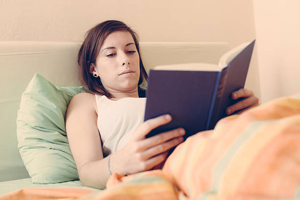 istock Young Woman Reading a Book on the Bed 539058457