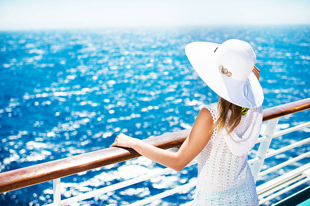 Woman enjoying on a cruise. Unrecognizable woman with hat on a cruise ship looking at the view. cruise ship photos stock pictures, royalty-free photos & images