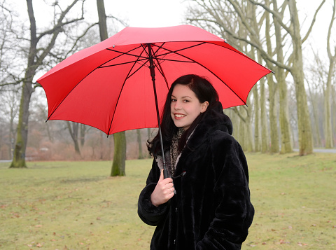 Germany, Berlin, cheerful young woman with red umbrella in park