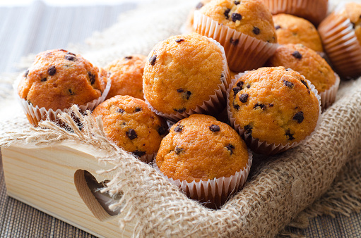 Little chocolate muffins in paper cupcake holder on the wooden tray with sacking napkin