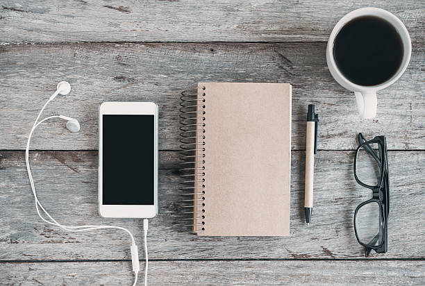 cellphone and earphone with a cup of coffee on wooden table, Top view