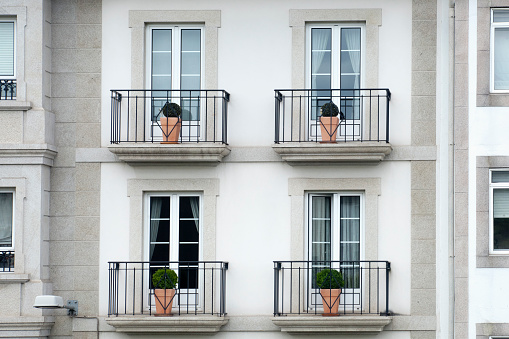 Architectural details of modern high apartment building facade with many windows and balconies.