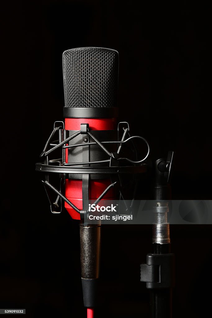 Recording studio red microphone with shock mount Professional recording studio condenser microphone attached to shock mount, isolated on black background Black Background Stock Photo