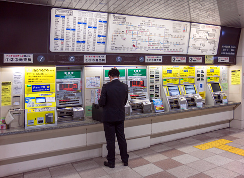 Nagoya, Japan, May 13, 2016; a man is buying a metro ticket from a wall filled with ticket vending machine at Kanayama station 