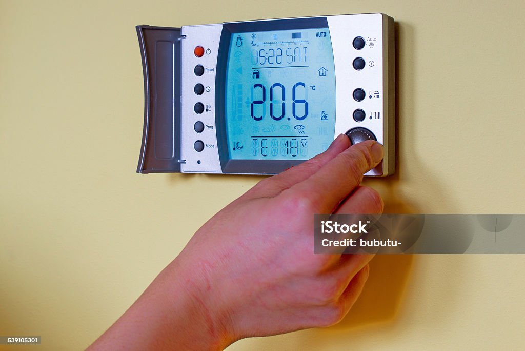 Closeup of a woman's hand setting the room temperature Closeup of a woman's hand setting the room temperature on a modern programmable thermostat (water heater)  - with copy space. Save energy and money concept Radiator - Heater Stock Photo