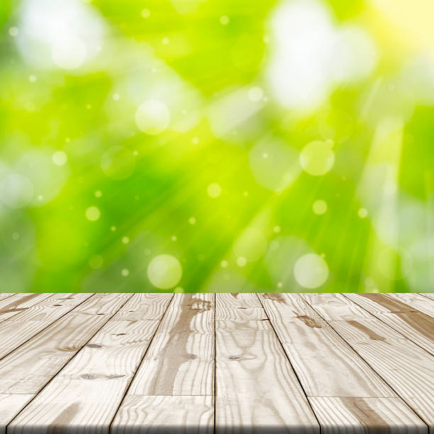 istock Wood table top on green blurred in background with sunlight 539106332