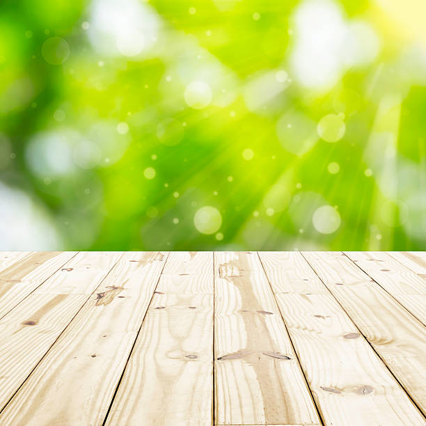 istock Wood table top on green blurred in background with sunlight 539106382