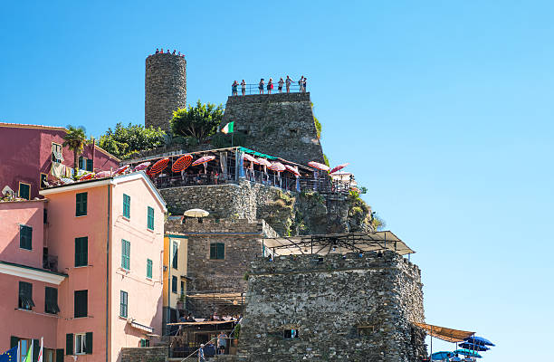 Vernazza, Italy - September 7, 2015: The old fortress on the sea ad the typical tower-houses with tourists looking at the panorama.