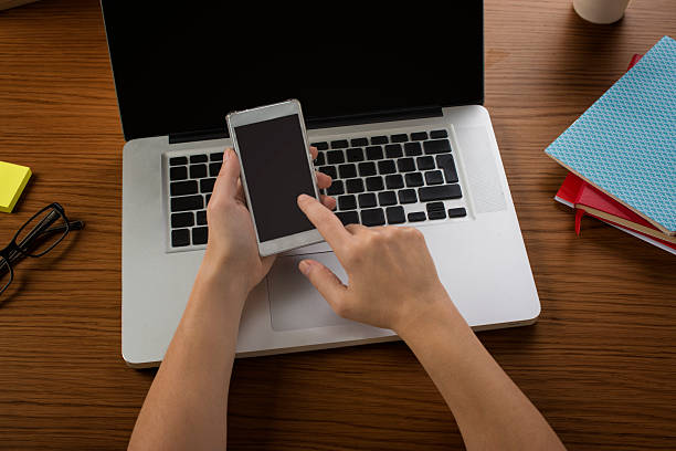 istock Female hand holding a smartphone with a laptop on side 539107406