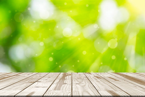 istock Wood table top on green blurred in background with sunlight 539107512