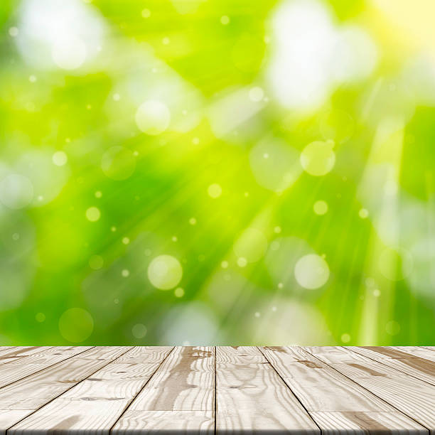 istock Wood table top on green blurred in background with sunlight 539108250