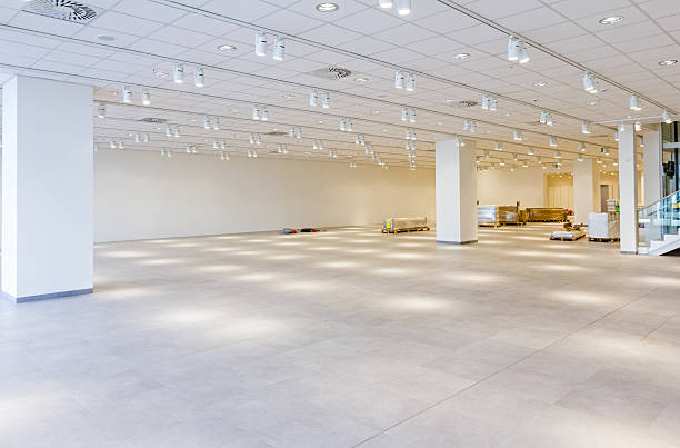 View on large showroom in a modern business centre. Furnishing equipment is on the floor for white room with ceiling light. ceiling tile lighting stock pictures, royalty-free photos & images