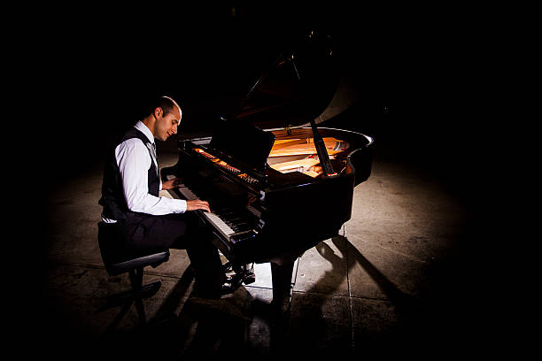 mann spielt klavier mit dramatische beleuchtung - pianist stock-fotos und bilder