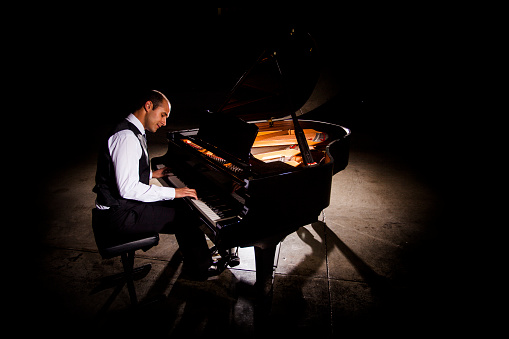 Hombre tocando Piano con una iluminación dramática photo