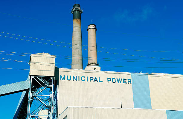 Cooling towers and smoke stacks of a coal fired power plant against a cloudy sky.  Water vapour from the cooling tower and smoke from the chimney.